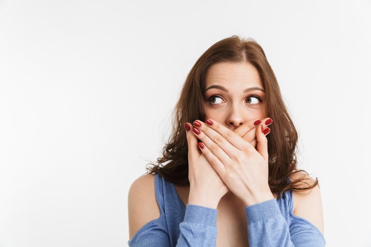 Portrait of a surprised young woman covering mouth
